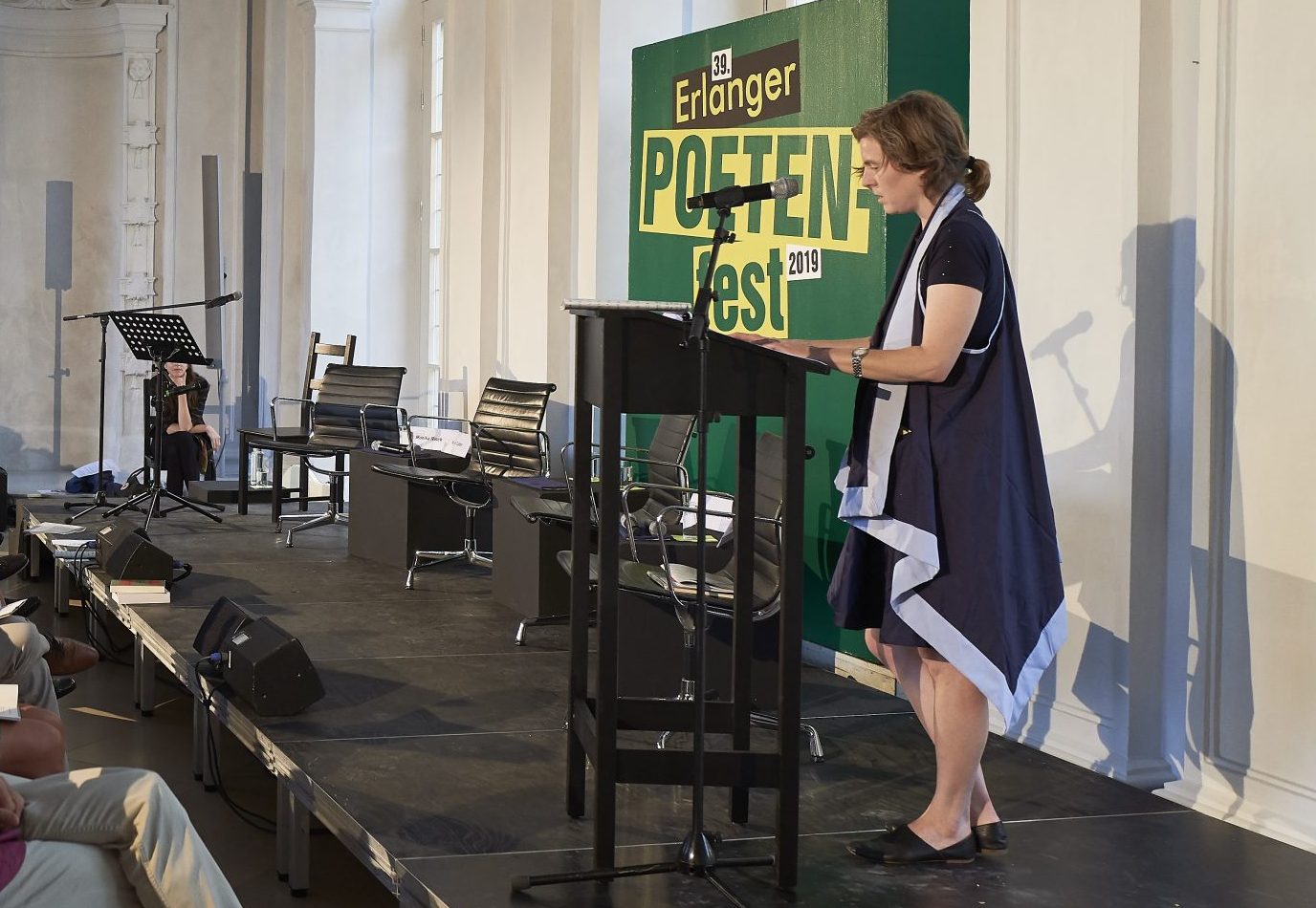 Ann Cotten auf dem Podium vor einer grünen Leinwand welche mit 'Erlanger Poetenfest 2019' beschriftet ist